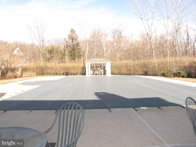 view of pool with a patio, a covered pool, an outbuilding, a gazebo, and an exterior structure