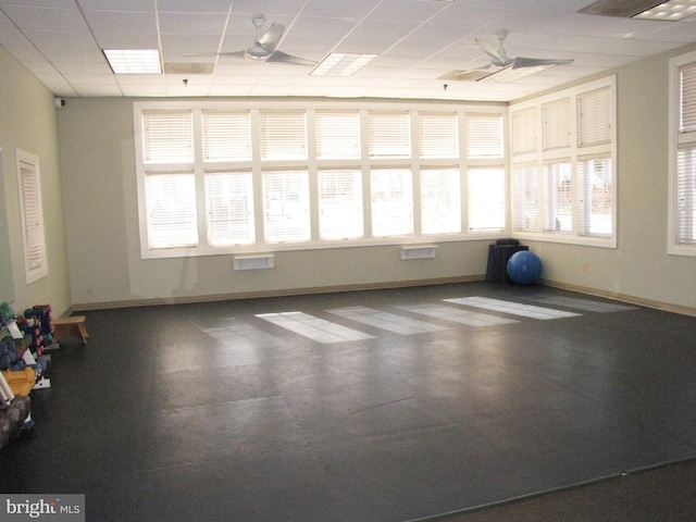 exercise area featuring a paneled ceiling and baseboards