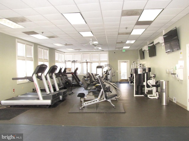 gym featuring a drop ceiling, ceiling fan, baseboards, and a wall mounted AC