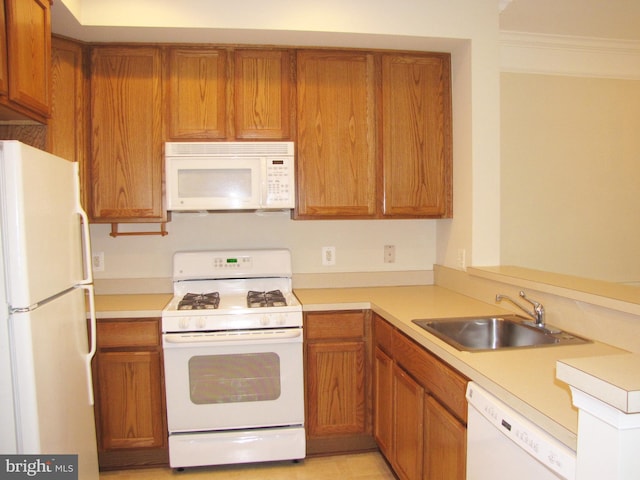 kitchen with white appliances, light countertops, a sink, and brown cabinetry