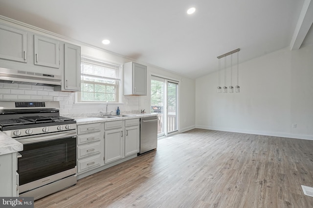 kitchen featuring lofted ceiling, under cabinet range hood, a sink, light countertops, and appliances with stainless steel finishes