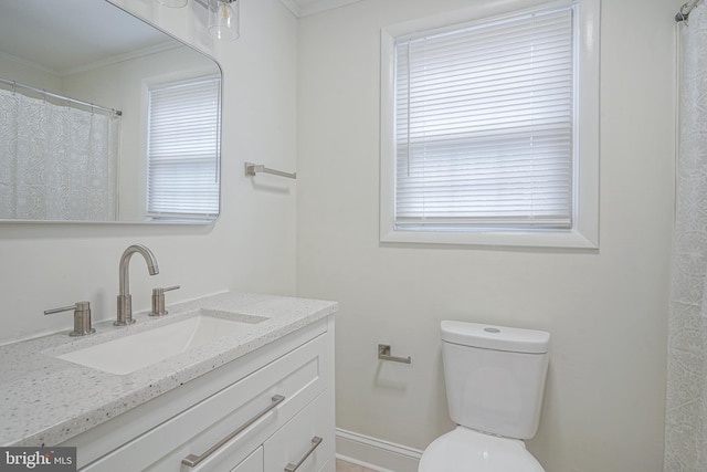 bathroom featuring a healthy amount of sunlight, toilet, crown molding, and vanity