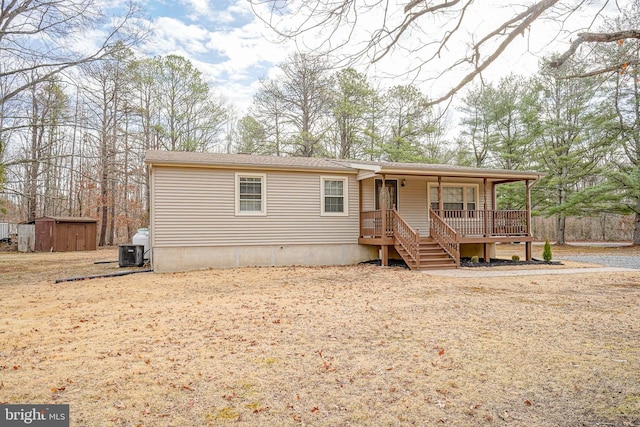 view of front facade featuring a shed, central AC unit, a porch, and an outdoor structure