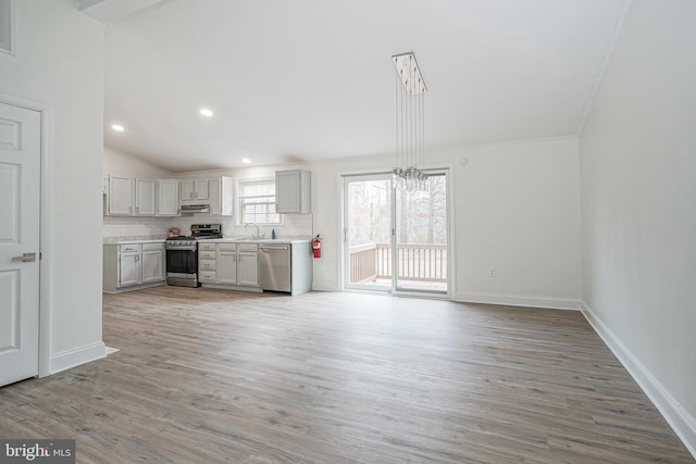 kitchen with stainless steel appliances, a sink, light countertops, light wood finished floors, and tasteful backsplash