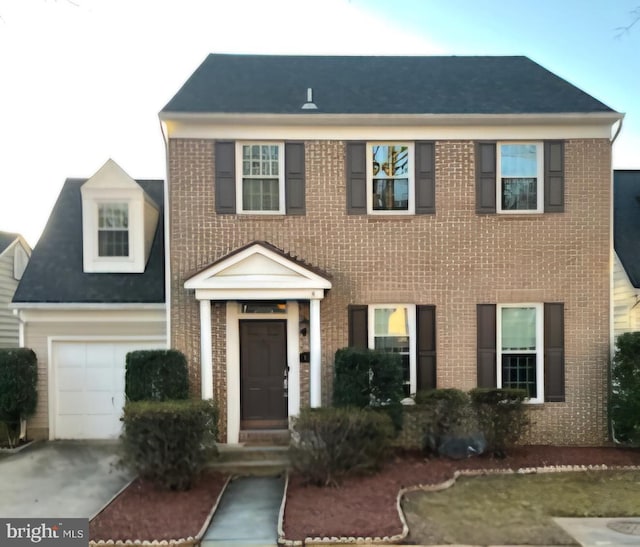 colonial house with driveway and brick siding