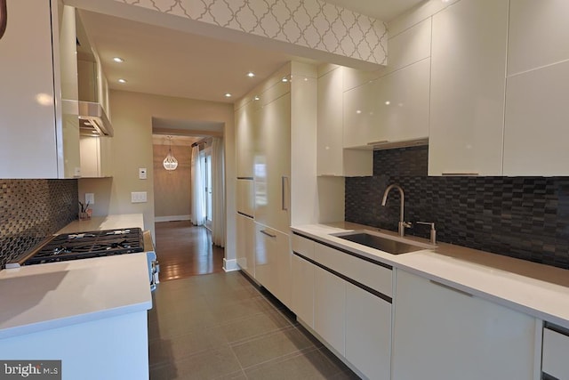 kitchen with backsplash, light countertops, white cabinets, modern cabinets, and a sink