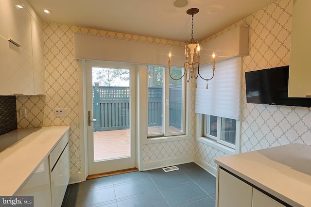 interior space featuring a chandelier, visible vents, wallpapered walls, and dark tile patterned flooring