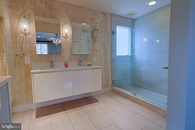 full bath with a sink, baseboards, double vanity, and a shower stall