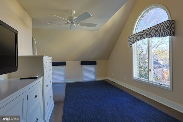 bonus room featuring lofted ceiling, baseboards, dark wood-type flooring, and ceiling fan