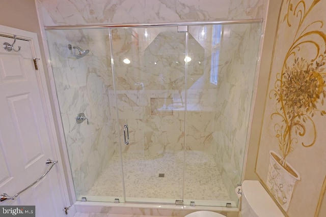 bathroom featuring toilet and a marble finish shower