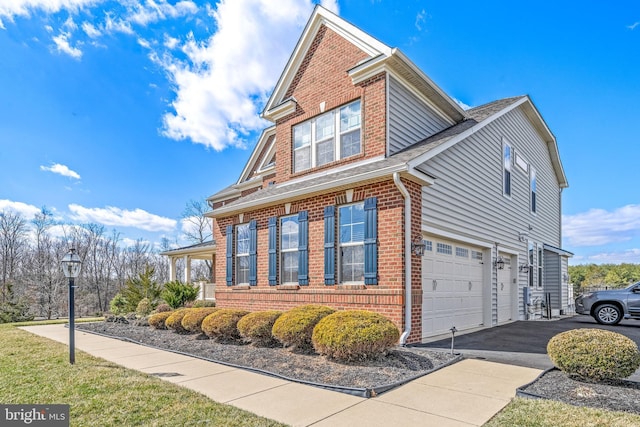 view of side of home with aphalt driveway, brick siding, and a garage