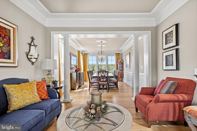 living room featuring light wood-style flooring, ornamental molding, and ornate columns