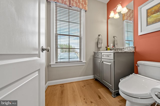 bathroom featuring vanity, toilet, wood finished floors, and baseboards