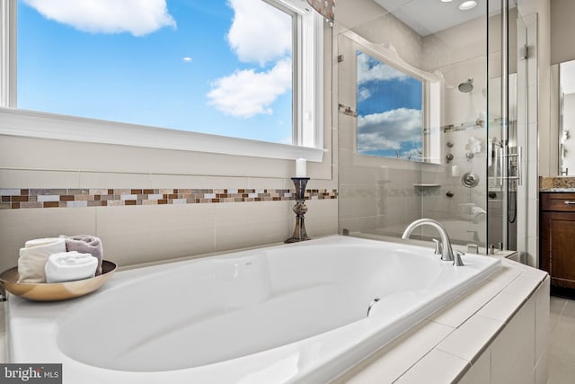 bathroom featuring vanity, a bath, and a shower stall