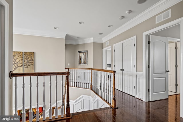 corridor with an upstairs landing, visible vents, wood-type flooring, and ornamental molding