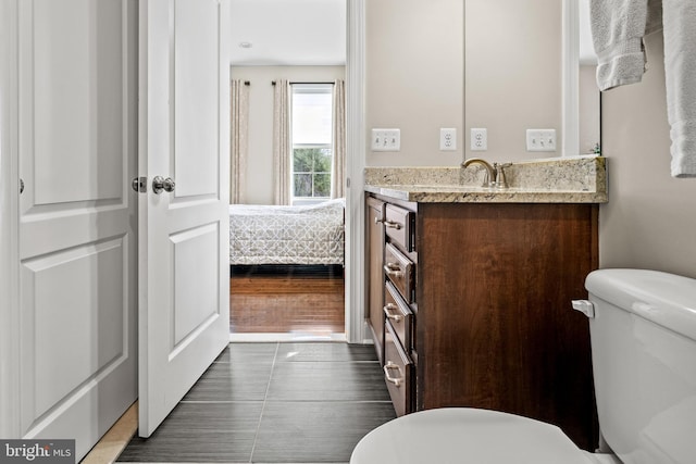 half bath featuring connected bathroom, toilet, vanity, and wood finished floors