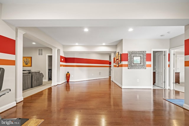 interior space featuring wood finished floors, visible vents, ornate columns, baseboards, and recessed lighting