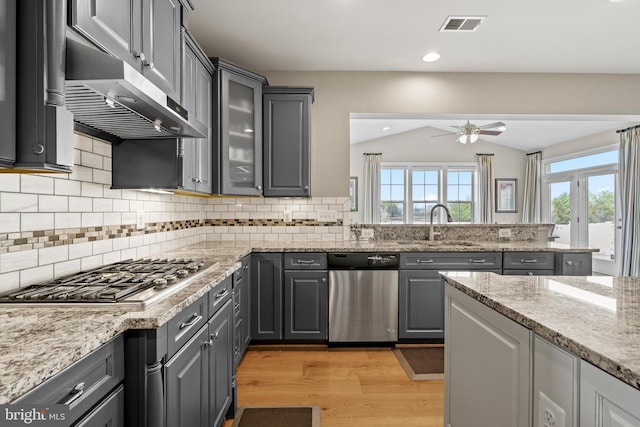 kitchen with visible vents, gray cabinets, under cabinet range hood, appliances with stainless steel finishes, and lofted ceiling