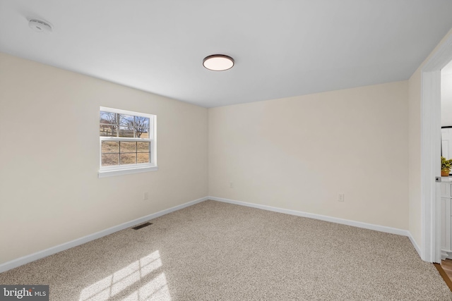 carpeted spare room featuring visible vents and baseboards