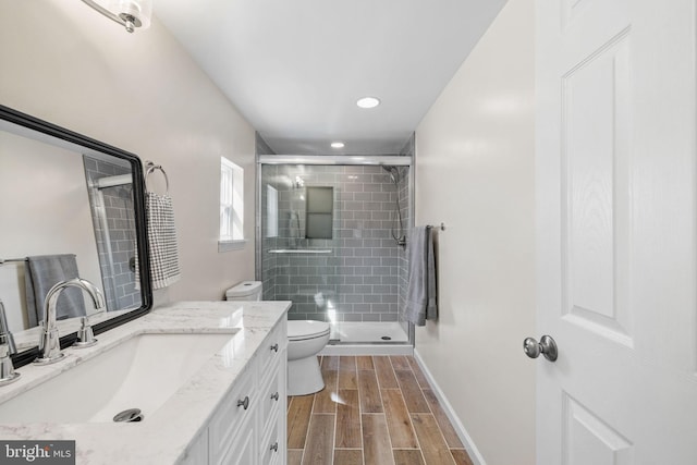 full bath featuring wood finish floors, toilet, a shower stall, baseboards, and vanity