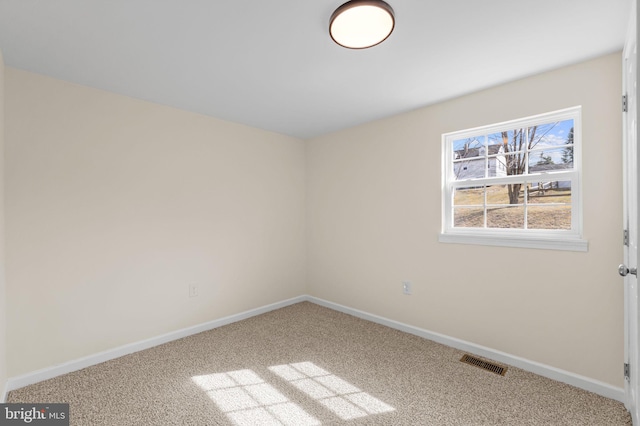 spare room with carpet flooring, baseboards, and visible vents