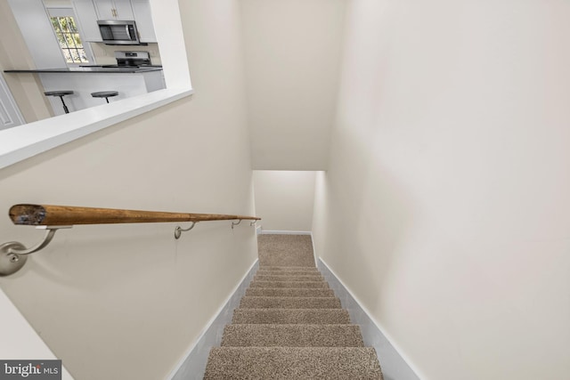 staircase with baseboards and carpet floors