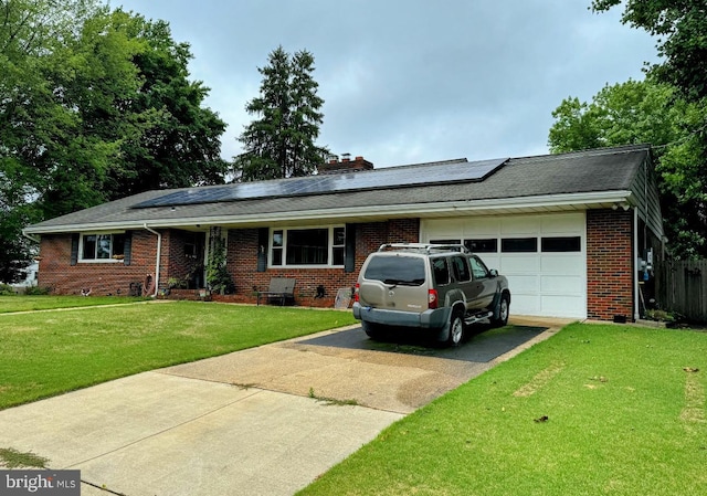 single story home featuring an attached garage, brick siding, concrete driveway, roof mounted solar panels, and a front yard