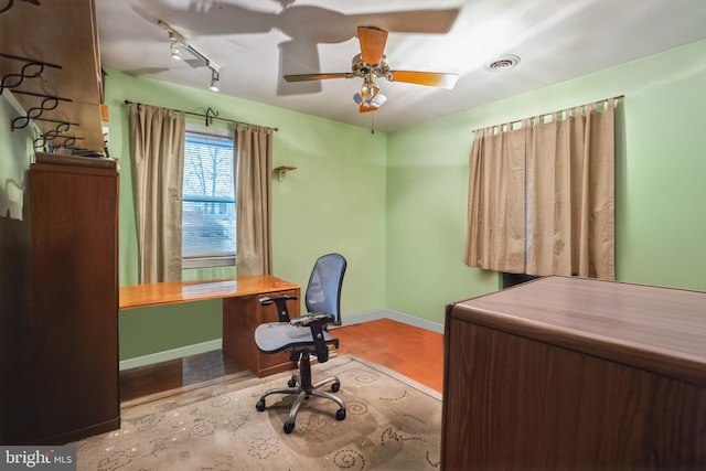 home office with visible vents, track lighting, wood finished floors, baseboards, and ceiling fan