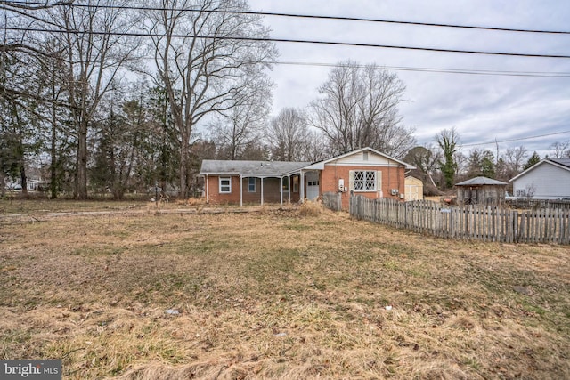 view of front of house with a front lawn, fence, and brick siding