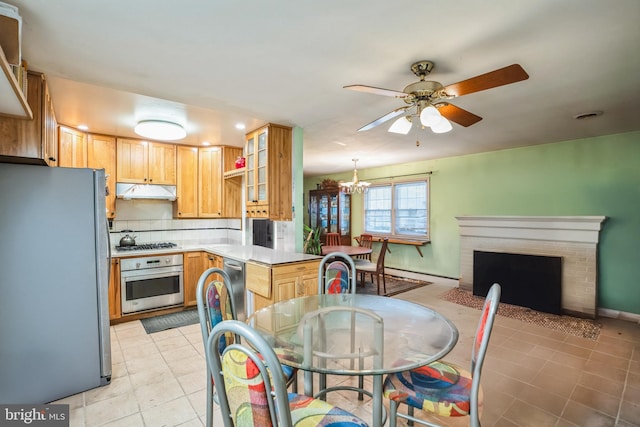 kitchen featuring glass insert cabinets, under cabinet range hood, a peninsula, light tile patterned flooring, and stainless steel appliances