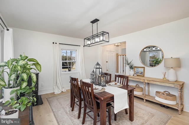 dining area featuring baseboards, light wood-style floors, and a chandelier