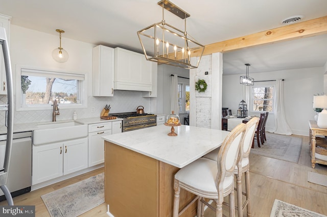 kitchen featuring stainless steel range, a sink, decorative backsplash, light stone countertops, and dishwasher