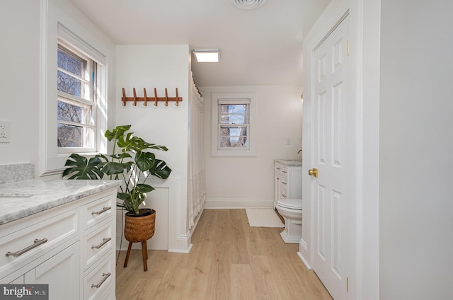 bathroom featuring toilet, vanity, baseboards, and wood finished floors