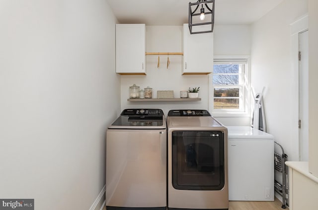 clothes washing area featuring cabinet space and separate washer and dryer