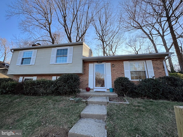 tri-level home with brick siding and a front yard