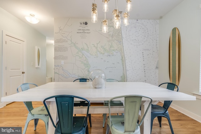 dining space featuring an accent wall, light wood-style flooring, and baseboards