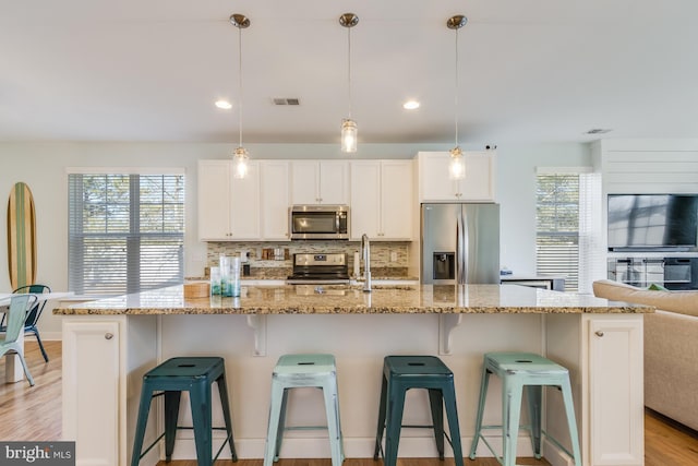 kitchen with plenty of natural light, tasteful backsplash, visible vents, and stainless steel appliances