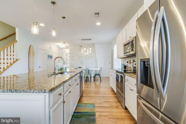 kitchen featuring visible vents, light wood-style flooring, appliances with stainless steel finishes, white cabinetry, and a sink