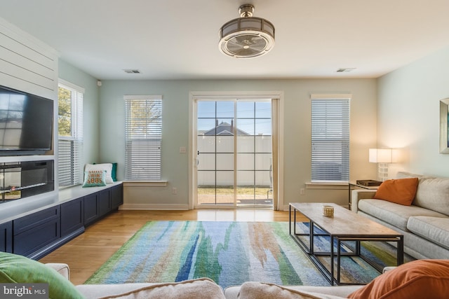 living area featuring light wood-style floors, visible vents, and baseboards