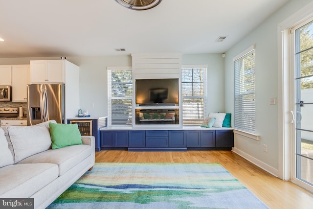 living area with baseboards, visible vents, and light wood finished floors