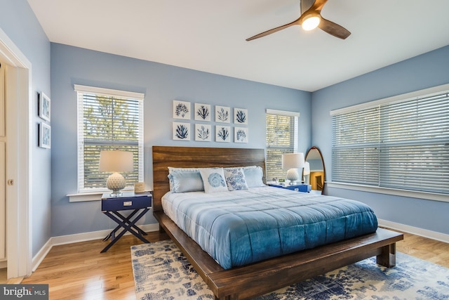 bedroom featuring multiple windows, light wood-type flooring, and baseboards