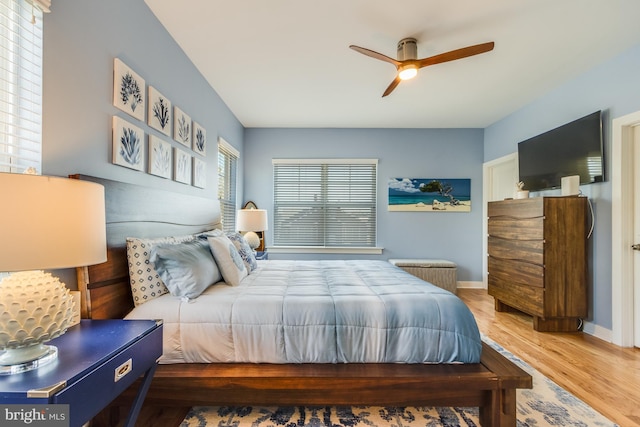 bedroom with light wood-type flooring, a ceiling fan, and baseboards