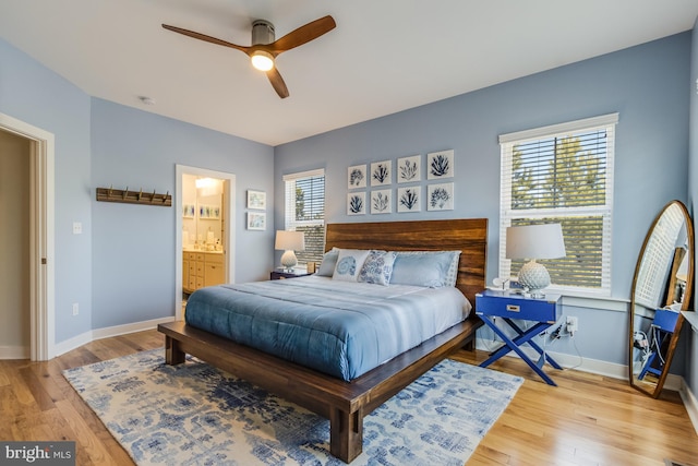 bedroom featuring baseboards, ensuite bath, and light wood finished floors