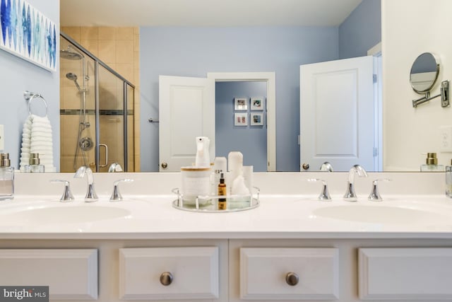 full bathroom with double vanity, a shower stall, and a sink