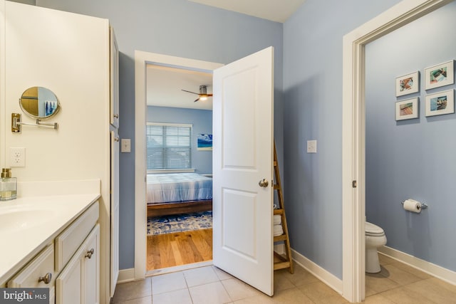 bathroom featuring toilet, connected bathroom, vanity, tile patterned flooring, and baseboards