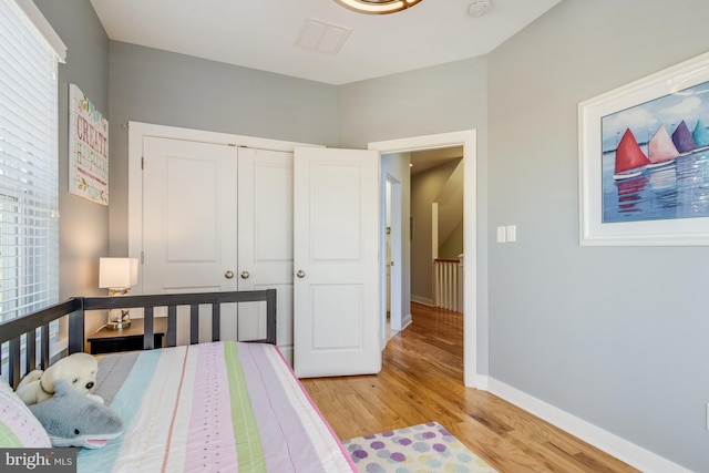 bedroom with light wood-style floors, a closet, visible vents, and baseboards