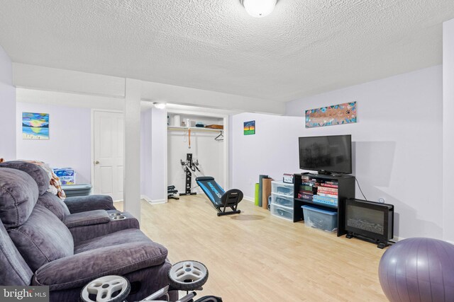 living room featuring a textured ceiling, baseboards, and wood finished floors
