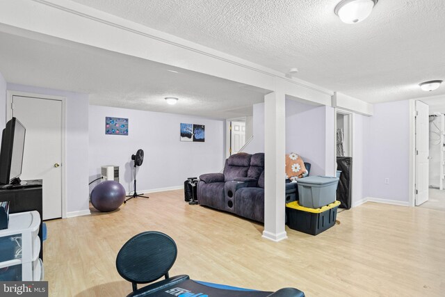 exercise room featuring wood finished floors, baseboards, and a textured ceiling