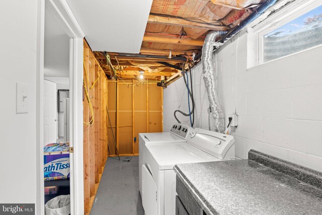 clothes washing area featuring laundry area, concrete block wall, and washing machine and dryer