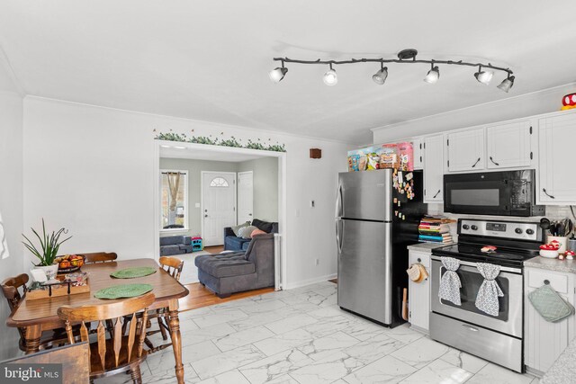 kitchen featuring light countertops, ornamental molding, appliances with stainless steel finishes, white cabinets, and marble finish floor
